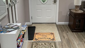 A hallway with a white door, a welcome mat, a coat rack, and a small table with a lamp. - Luxurious, private, contemporary 1BR apartment in Ithaca NY!  (Ithaca)