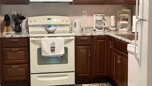 A kitchen with wooden cabinets, a white stove, a microwave, a coffee maker, and a refrigerator. - Luxurious, private, contemporary 1BR apartment in Ithaca NY!  (Ithaca)