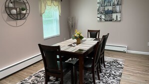 A dining room with a table set for four, surrounded by chairs, a decorative wall piece, and a window with curtains. - Luxurious, private, contemporary 1BR apartment in Ithaca NY!  (Ithaca)