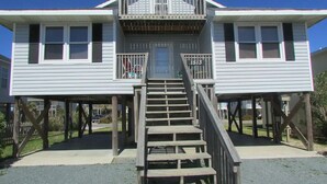 A two-story house with a balcony and a staircase leading to the entrance. - Just steps to the beach, bar, and playground park! (Surf City)