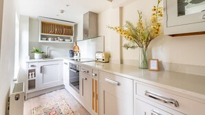 Eine moderne Küche mit weißen Schränken, einer Glasrückwand und einem Blumenstrauß auf der Arbeitsfläche.