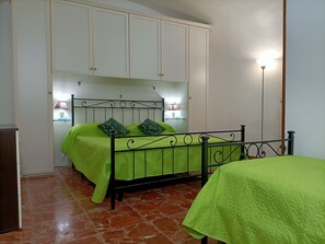 Ein Schlafzimmer mit Bett, Nachttisch, Lampe und Kleiderschrank.