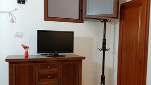 Una habitación con un armario de madera, televisor, un trípode y una puerta.