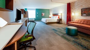 Ett hotellrum med ett skrivbord, en stol, en säng och en soffa.