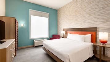 Habitación de hotel con cama, escritorio, silla, ventana y pared con textura.