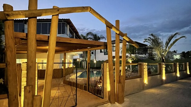 Une structure en bois avec une porte, une piscine et un bâtiment en arrière-plan.