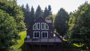 Ein zweistöckiges Haus mit einer Terrasse, umgeben von Bäumen.