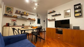 A compact living space with a kitchenette, a dining area, a sofa, and a TV. - Living Rencio casa vacanza a Bolzano (Bolzano)