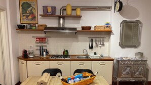 A kitchen with a stove, sink, and cabinets. There are shelves above the stove holding various items. - Living Rencio casa vacanza a Bolzano (Bolzano)