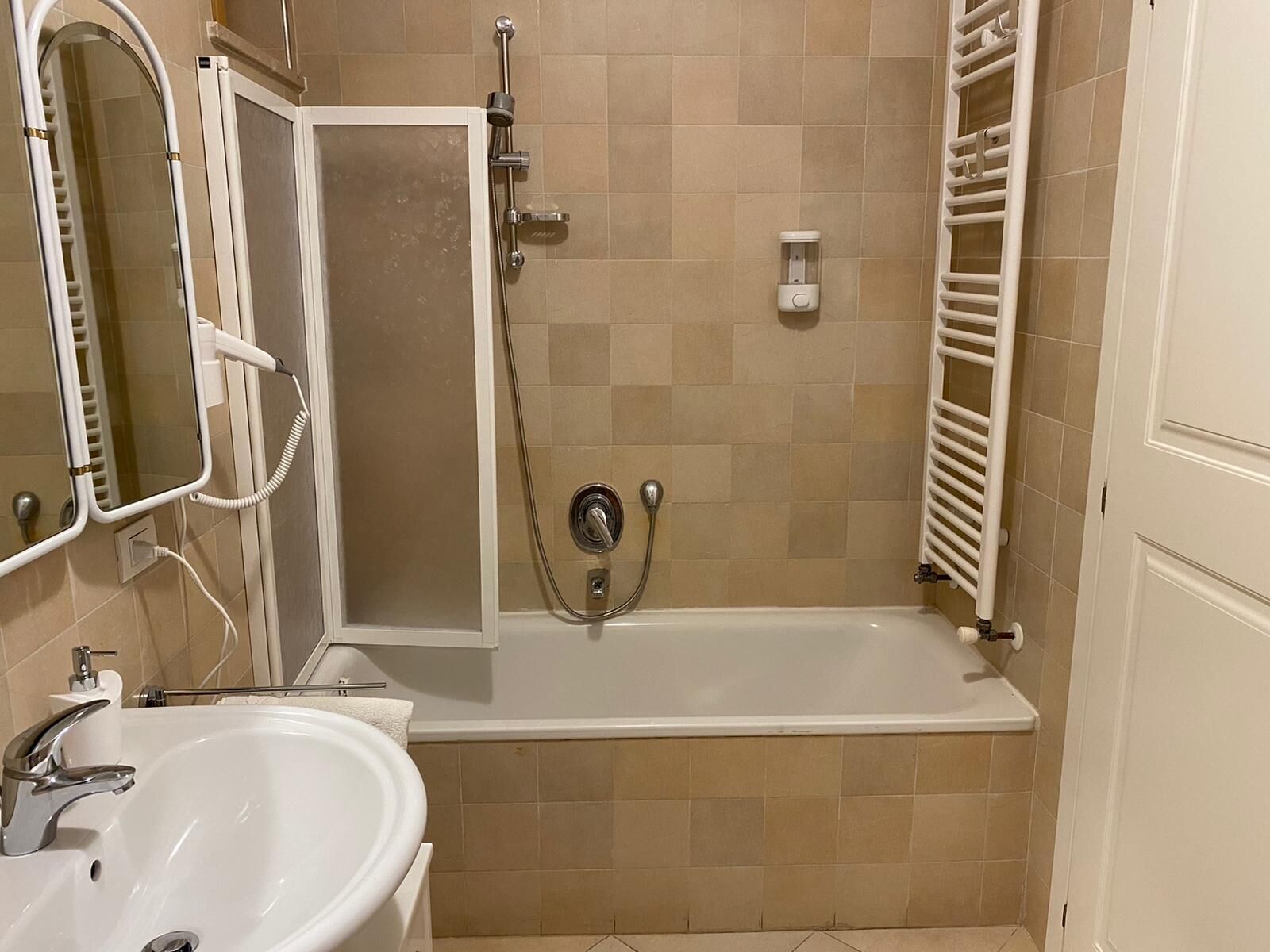 A bathroom with a bathtub, a shower, a sink, and a mirror.