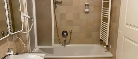 A bathroom with a bathtub, a shower, a sink, and a mirror.