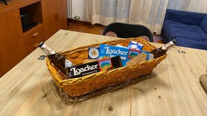 A wicker basket filled with snacks and drinks on a wooden table in a living room. - Living Rencio casa vacanza a Bolzano (Bolzano)