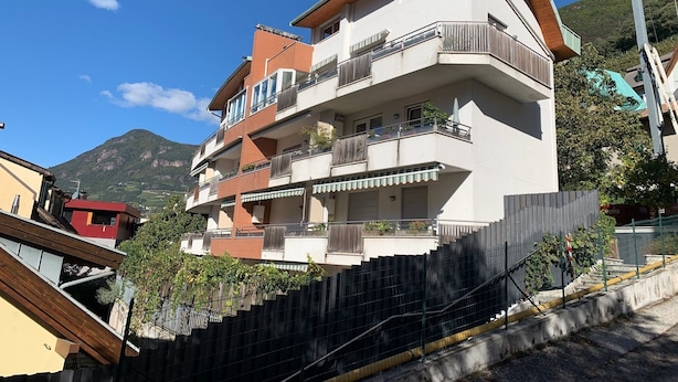 A multi-story building with balconies, a wooden facade, and a mountainous backdrop. - Living Rencio casa vacanza a Bolzano (Bolzano)