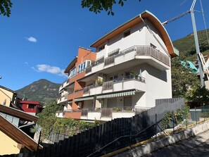 A multi-story building with balconies, a wooden facade, and a mountainous backdrop. - Living Rencio casa vacanza a Bolzano (Bolzano)