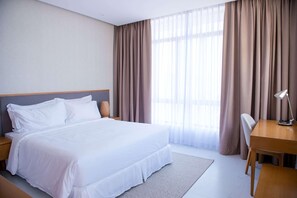 Une chambre d’hôtel avec un grand lit, un bureau et une chaise.