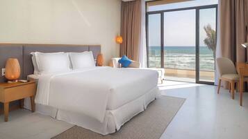 Habitación de hotel con una cama grande, un escritorio, una silla y vista al océano.