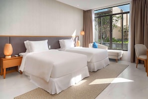 A hotel room with two beds, a sitting area with a chair, and a large window offering a view of the outdoors. - Wyndham Garden Cam Ranh Resort (Cam Ranh)