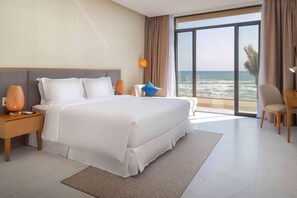 Una habitación de hotel moderna con una cama grande, una mesita de noche, un escritorio y vistas al océano.