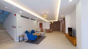 A modern living room with a sofa, coffee table, TV stand, and dining area.