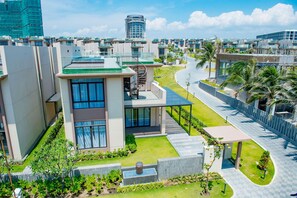 A modern residential building with a rooftop terrace, a covered outdoor seating area, and a well-maintained garden. - Wyndham Garden Cam Ranh Resort (Cam Ranh)
