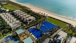 An aerial view of a resort with multiple buildings, a large swimming pool, and a beach. - Wyndham Garden Cam Ranh Resort (Cam Ranh)