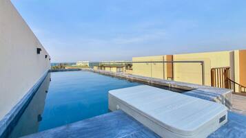 An infinity pool with a white infinity edge, a white infinity pool cover, and a clear blue sky.