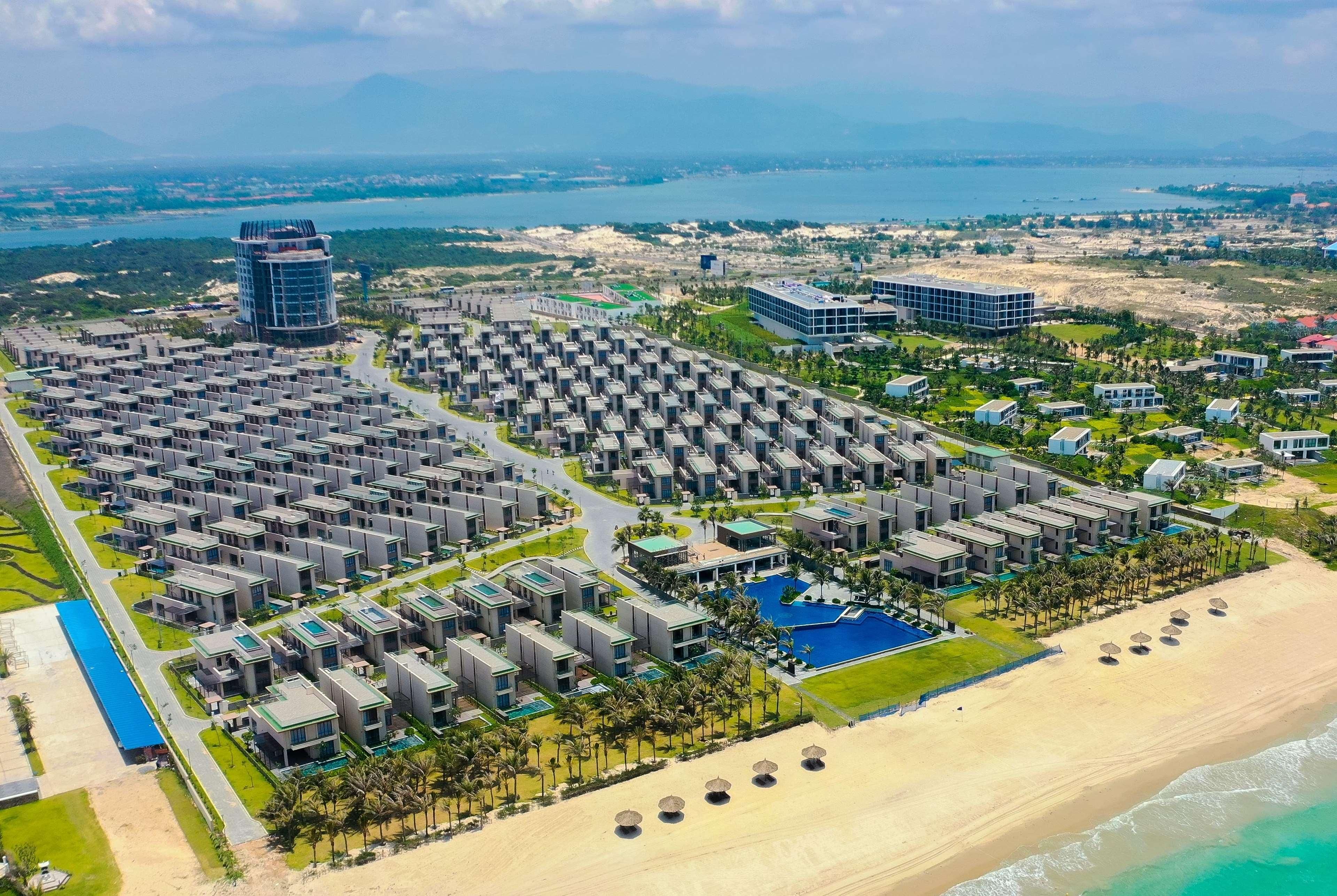 An aerial view of a resort with multiple buildings, a beach, and a pool area.
