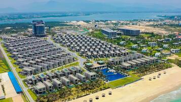 An aerial view of a resort with multiple buildings, a beach, and a pool area.