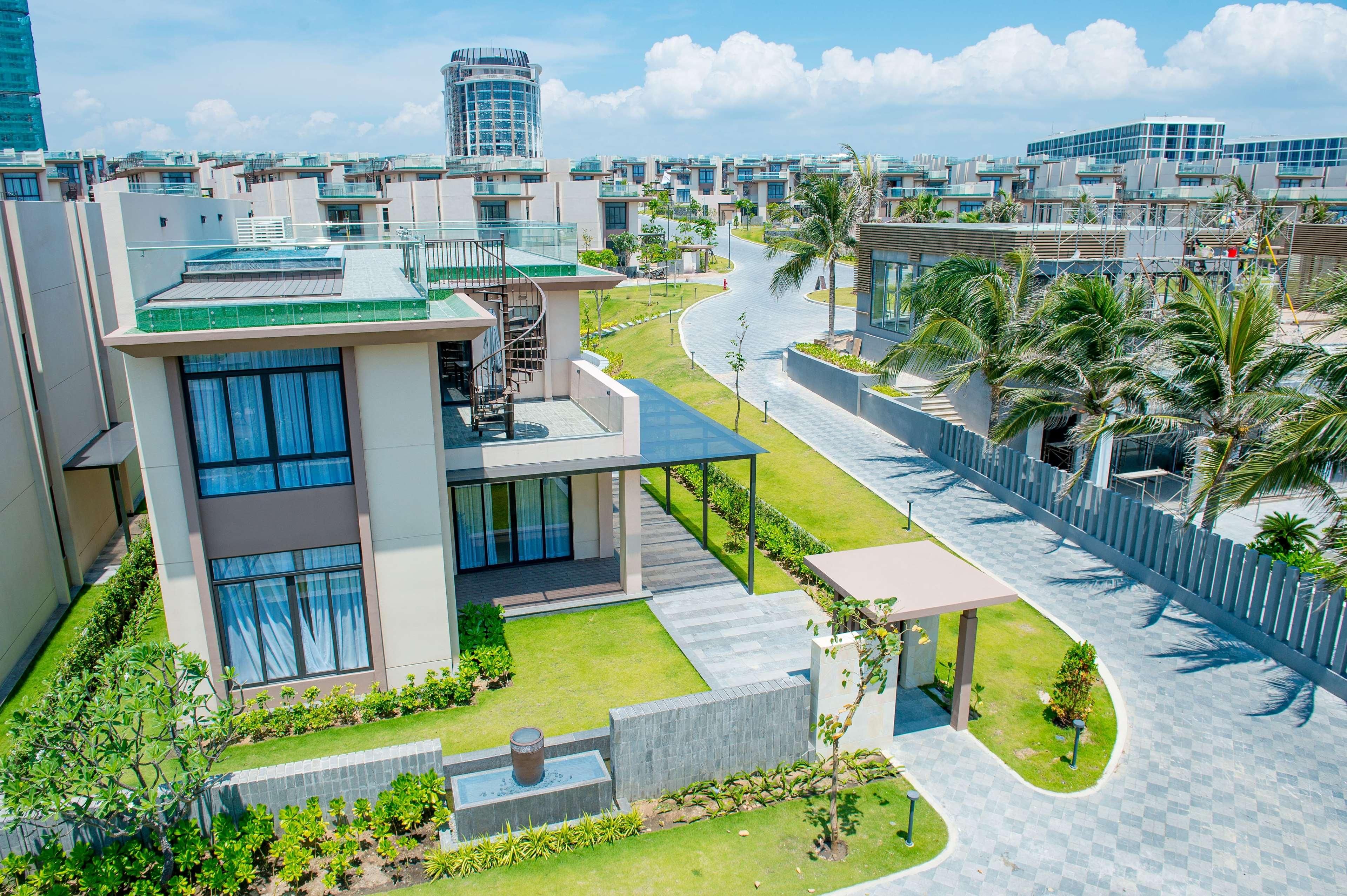 Un edificio residencial moderno con una terraza en la azotea, un camino curvo y un césped bien cuidado.
