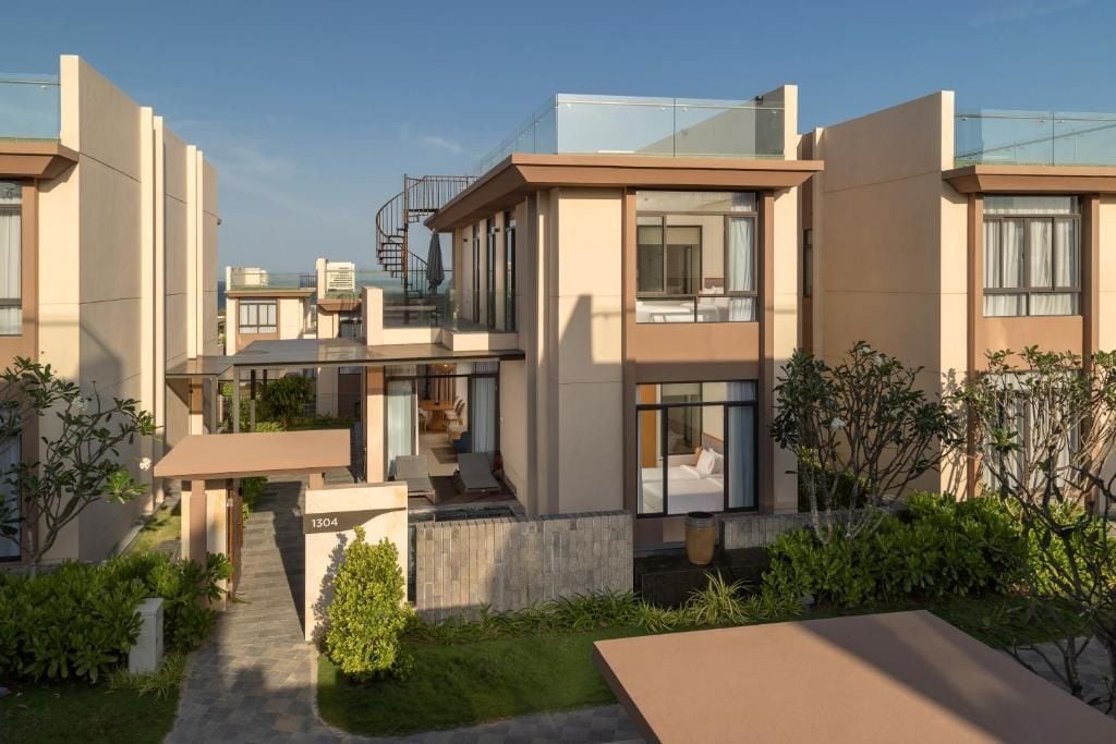 Ein modernes Wohngebäude mit Glasbalkon, sichtbarer Treppe und gepflegtem Gartenbereich.