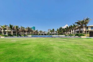 A grassy area with palm trees and buildings in the background. - Wyndham Garden Cam Ranh Resort (Cam Ranh)