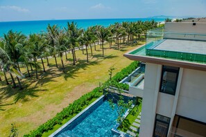 A modern hotel with a rooftop pool, a view of the beach, and palm trees. - Wyndham Garden Cam Ranh Resort (Cam Ranh)