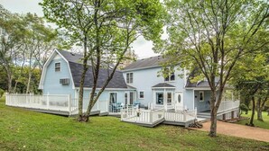 Een lichtblauw huis met een veranda en een omheind erf.