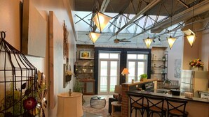 A modern kitchen with a bar area, large windows, and a high ceiling with exposed beams. - Green Door Lofts-Waco Rose - Silos/Downtown (Waco)
