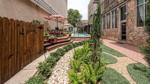 A courtyard with a wooden fence, outdoor seating, a pool, and a staircase leading to an upper level. - Green Door Lofts-Waco Rose - Silos/Downtown (Waco)