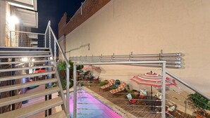 A rooftop pool area with a staircase, outdoor seating, and a metal railing. - Green Door Lofts-Waco Rose - Silos/Downtown (Waco)
