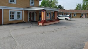 A motel with a covered entrance, a sign indicating it's open, and a parking lot with a white car. - North Bay Inn (North Bay)