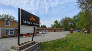 A North Bay Inn with a large sign, a parking lot, and a playground. - North Bay Inn (North Bay)