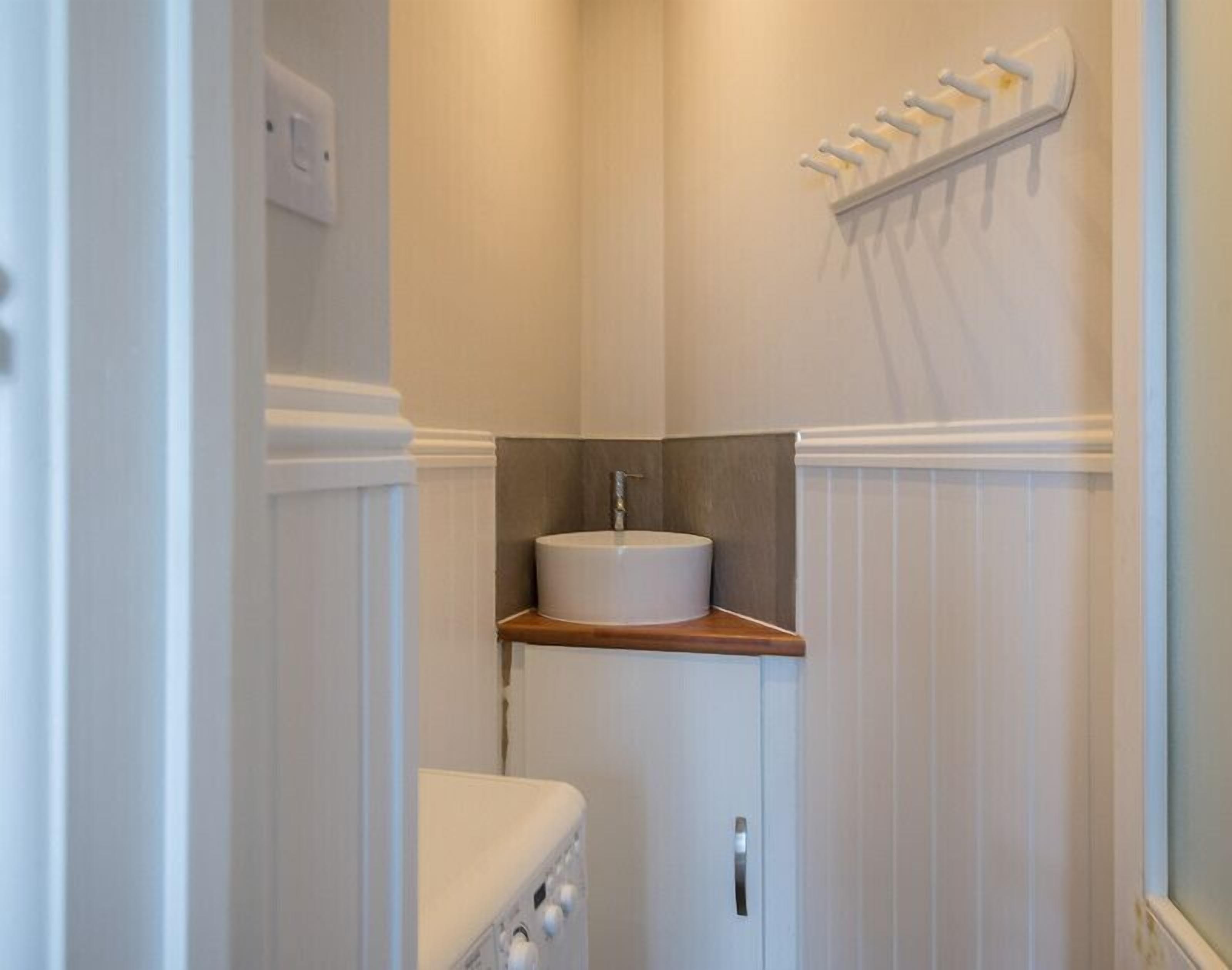 A small bathroom with a white sink, wooden countertop, and a towel rack on the wall.