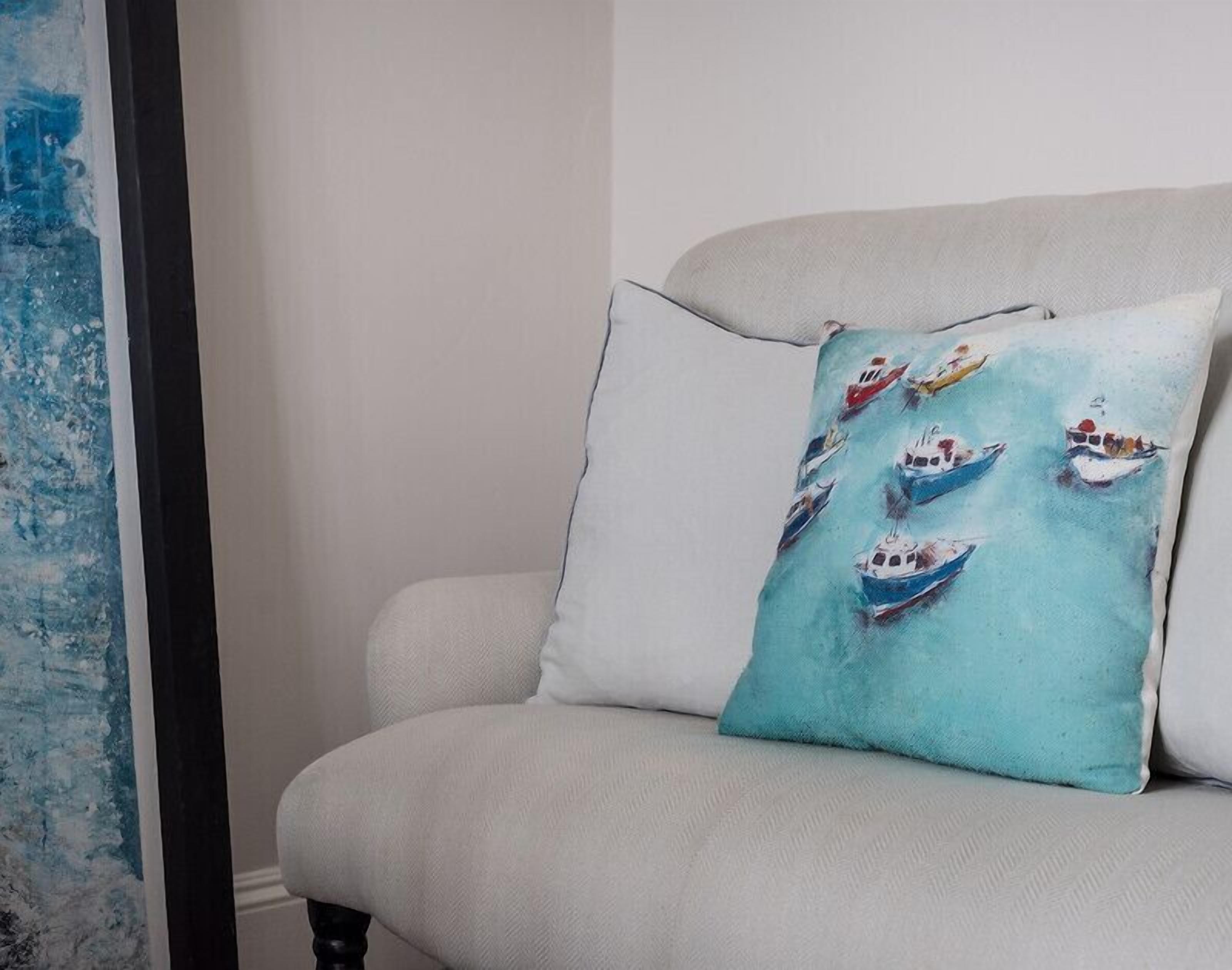 A light grey armchair with a teal pillow featuring a nautical theme.