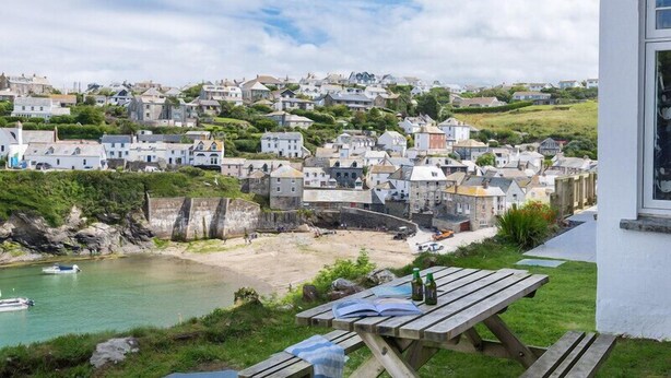 Ein Küstenort mit Steinhäusern, einem Strand und einem Picknicktisch mit Büchern und Flaschen.