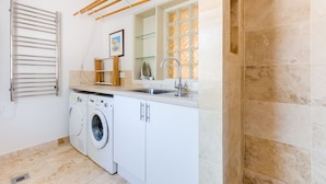 Een kleine keuken met een wasmachine, een spoelbak en een droogrek.