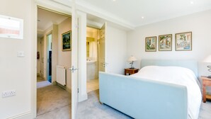 Een slaapkamer met een bed, nachtkastje, lamp en een deur naar een badkamer.