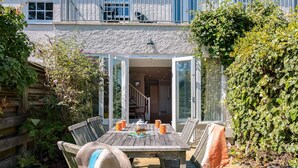 A wooden patio table with chairs, a hat, and orange mugs. - Lowenna Manor 4 (Wadebridge)