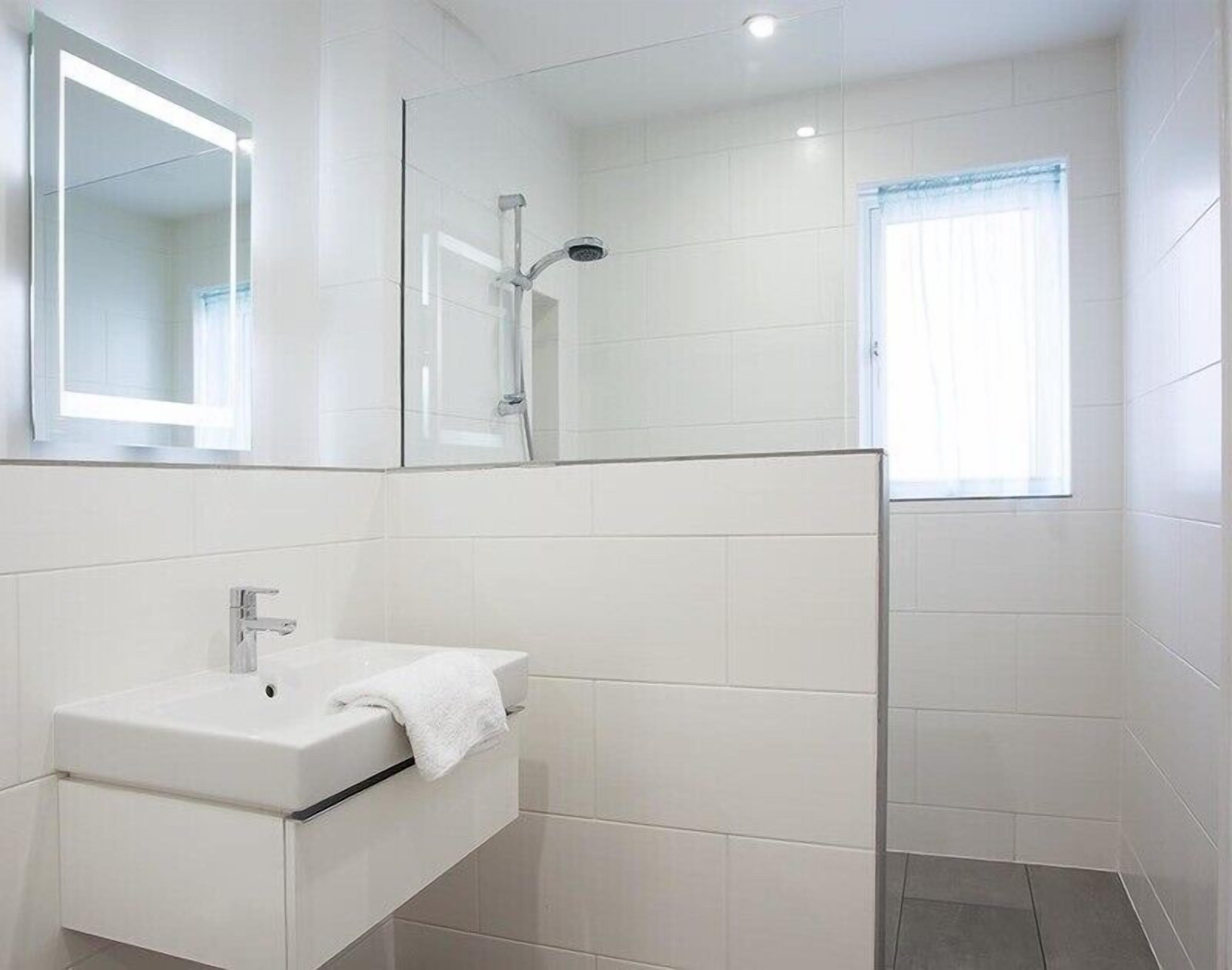 A modern bathroom with a white sink, mirror, and shower.