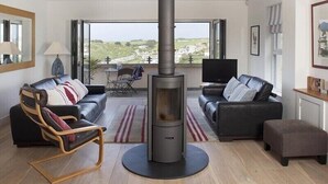 Una sala de estar moderna con chimenea, dos sofás, un sillón, un televisor y vistas al campo.