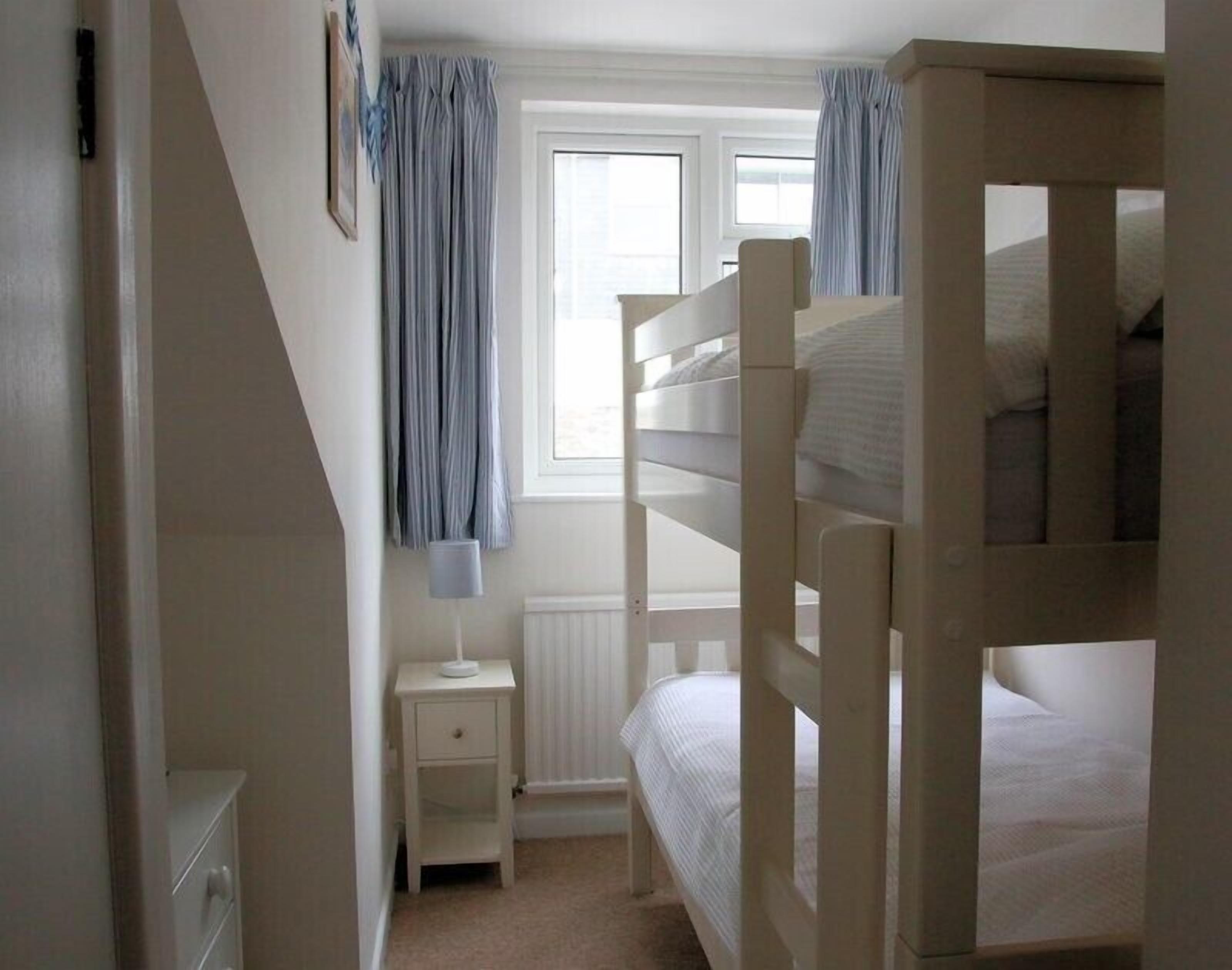 A bunk bed room with a window, a nightstand, and a radiator.