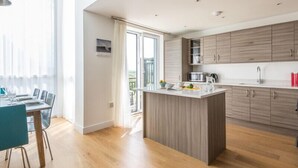 Una cocina moderna con armarios de madera, una isla central y un comedor con mesa y sillas.
