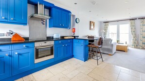 A modern kitchen with blue cabinets, a stainless steel range hood, and a built-in oven. - Rock Lobster (Port Isaac)