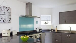 Een moderne keuken met een centraal eiland, een kookplaat, een spoelbak en een raam met zonwering.
